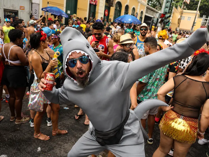 A man in a shark costume dancing in the middle of a street party