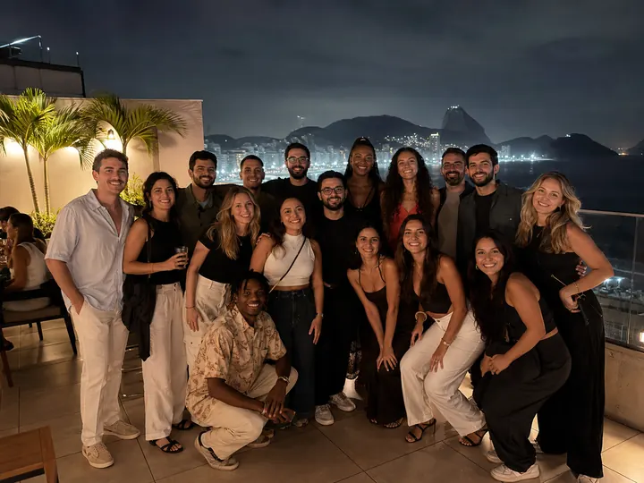 A group photo on a rooftop at night with the Rio skyline behind