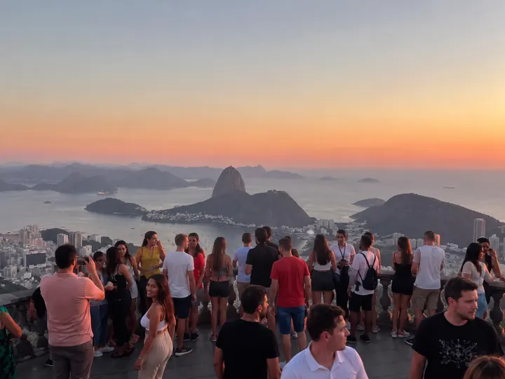 A crowd watching the sunset over Sugarloaf mountain from a viewpoint